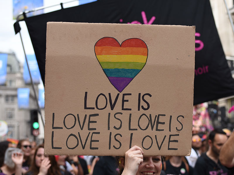 Một nhóm người giơ một tấm biển nói rằng tình yêu là tình yêu là tình yêu là tình yêu tại một cuộc diễu hành Pride.