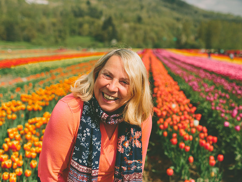 Một người phụ nữ đang học cách vượt qua cuộc ly hôn đang cười trên cánh đồng hoa tulip.
